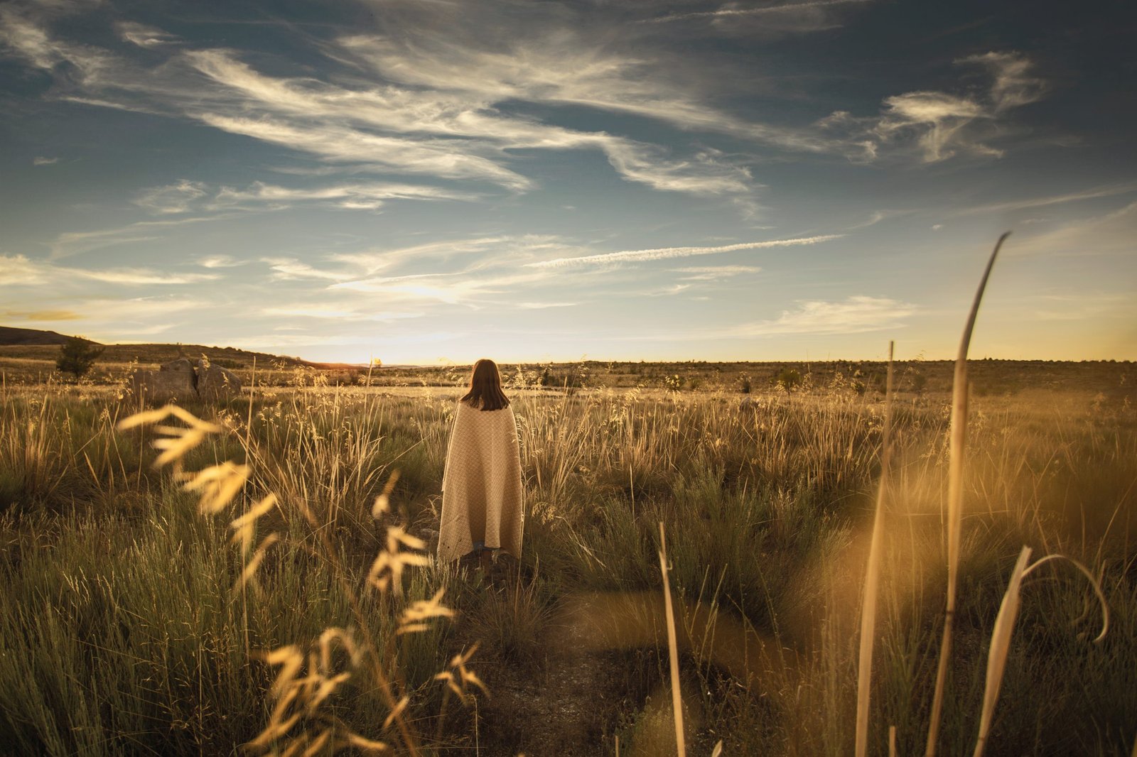 Woman curled up with a yellow blanket at sunset