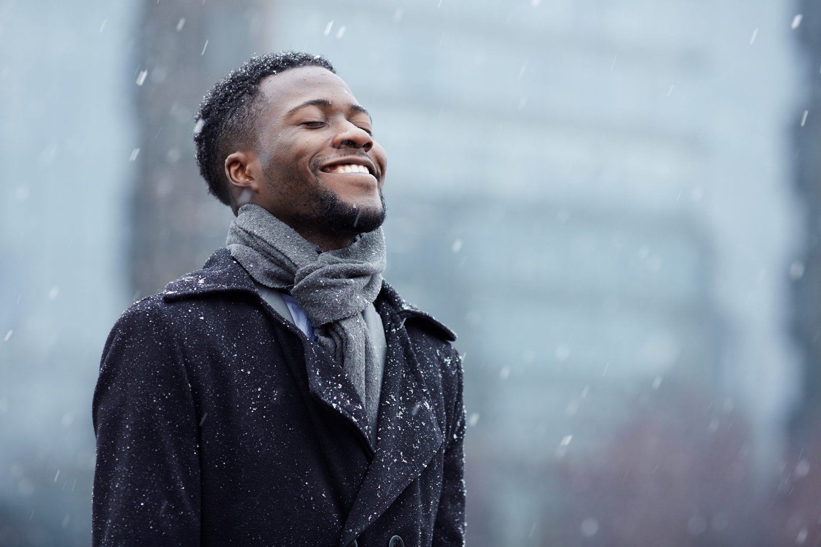 Cheerful man enjoying snowflakes falling from upwards