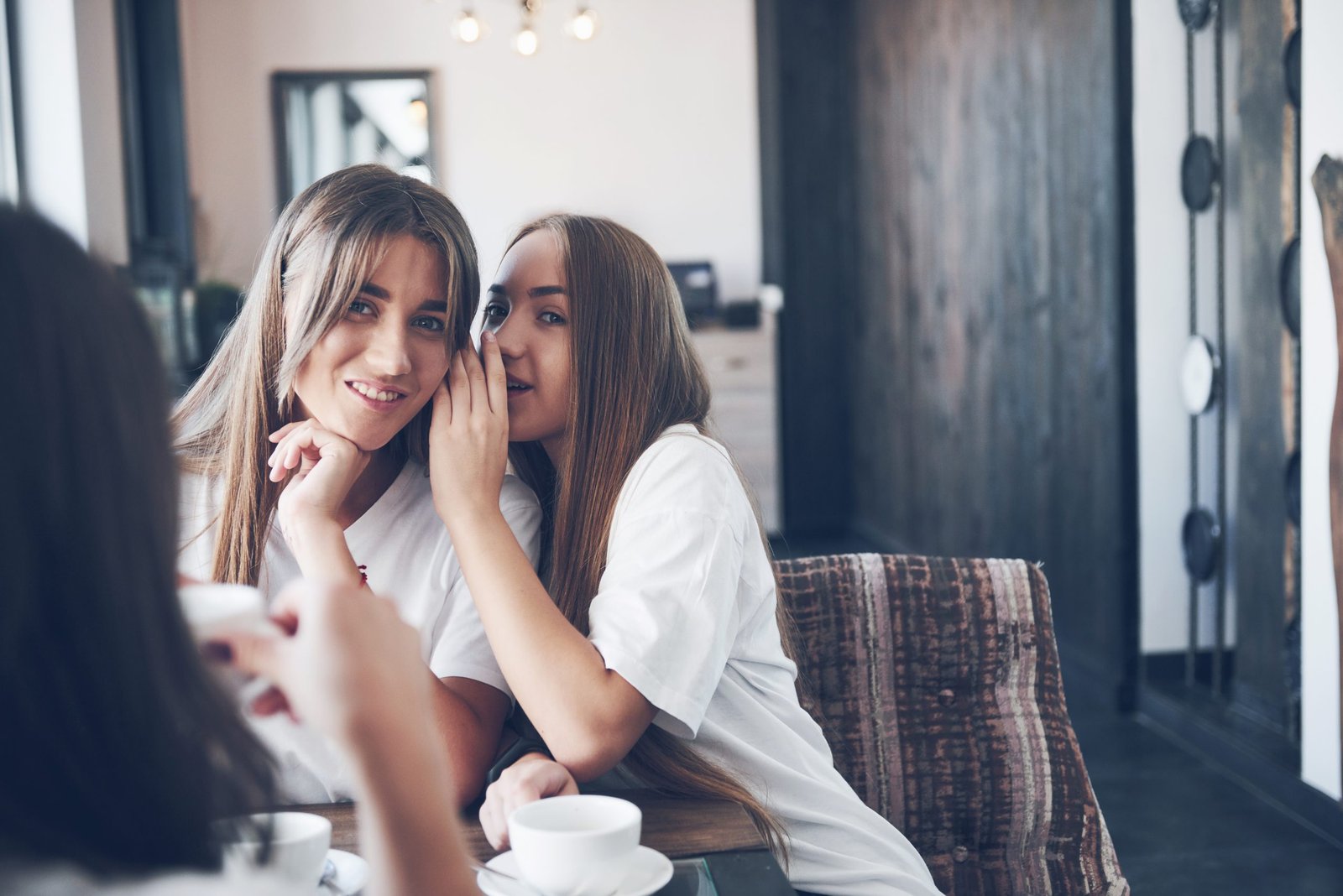 The three best girlfriends gathered to drink coffee and gossip. Girls having fun and laughing.