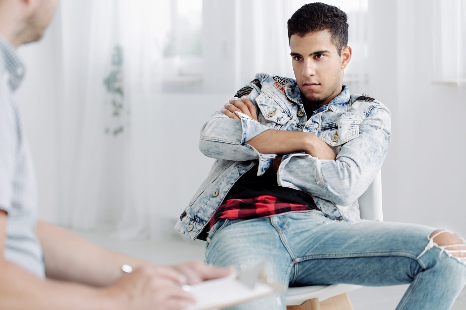 Rebellious spanish guy in the background during appointment with counselor