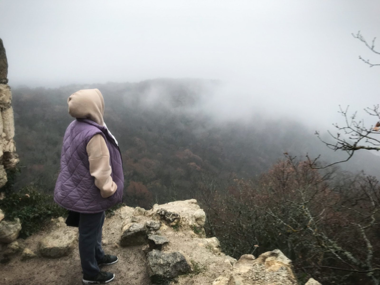 a-woman-stands-on-the-edge-of-a-mountain-fog-in-t-2022-01-04-18-53-51-utc