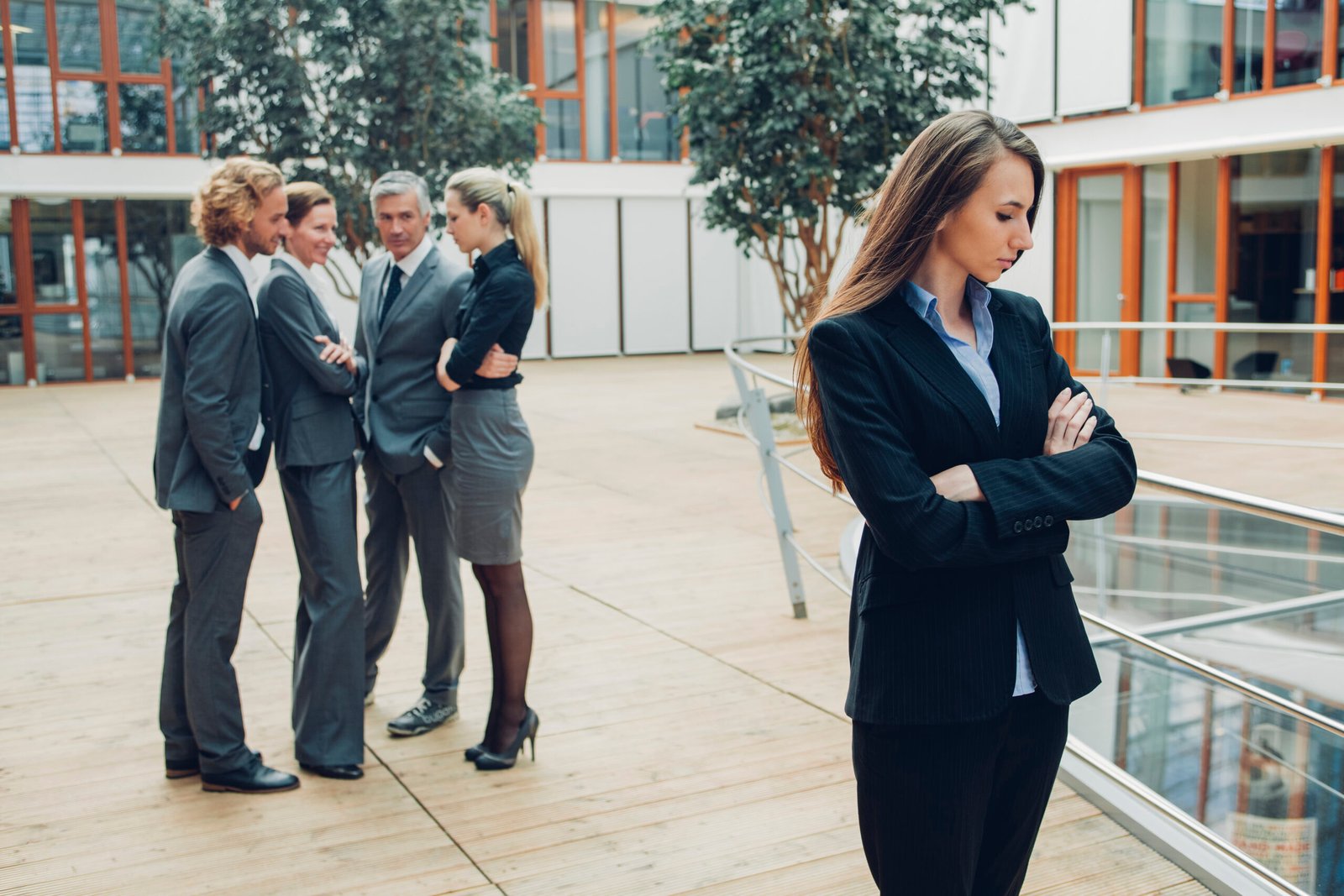 Businesswoman with crossed arms, excluded from group of business people