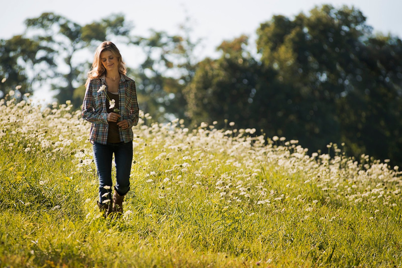 A young woman walking in a wild flower meadow.